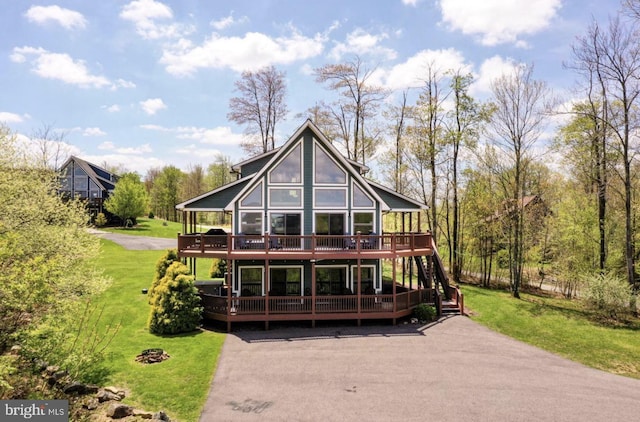 back of house with a wooden deck and a lawn