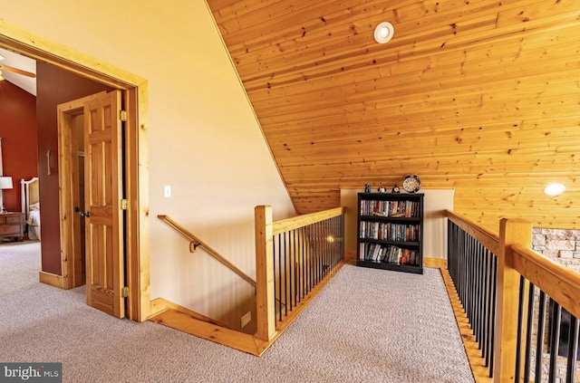 hall featuring light carpet, wooden walls, wood ceiling, and lofted ceiling