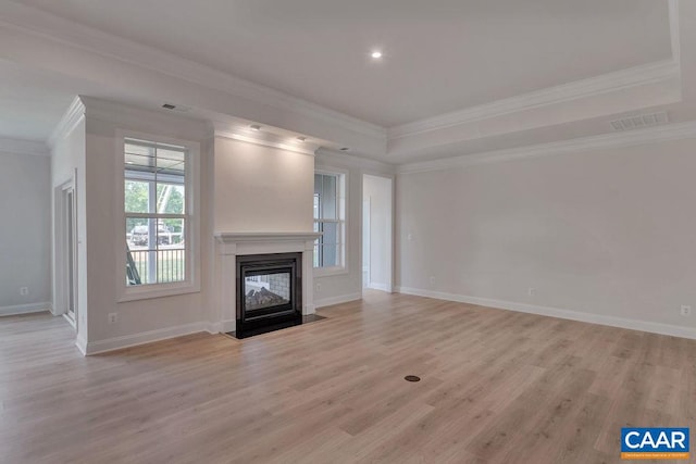 unfurnished living room featuring light wood-type flooring, a tray ceiling, and crown molding