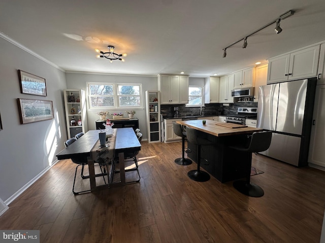 kitchen featuring white cabinetry, a kitchen breakfast bar, decorative backsplash, a kitchen island, and appliances with stainless steel finishes