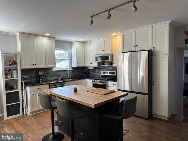 kitchen featuring butcher block counters, a breakfast bar, white cabinets, and appliances with stainless steel finishes