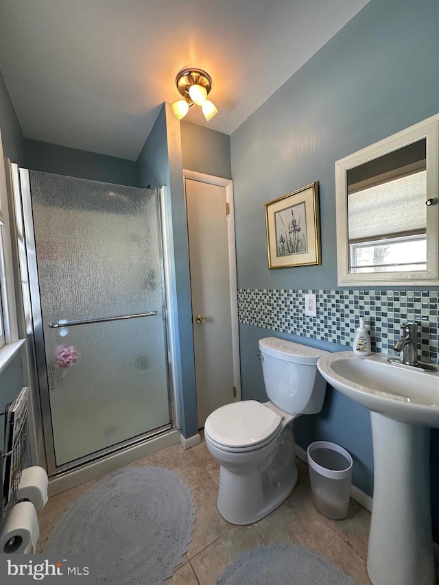 bathroom featuring tile patterned flooring, decorative backsplash, toilet, and an enclosed shower