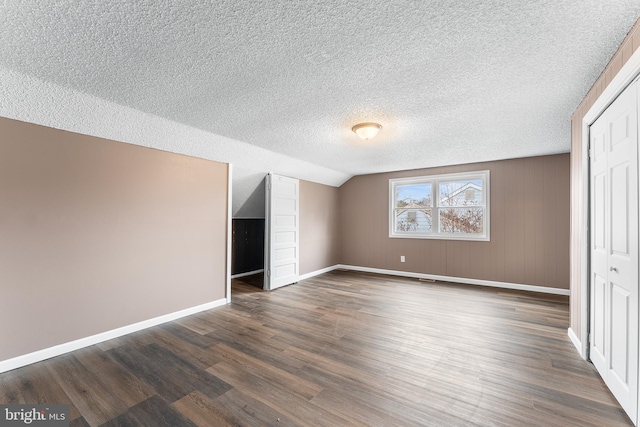 unfurnished bedroom with a textured ceiling, dark hardwood / wood-style floors, a closet, and lofted ceiling