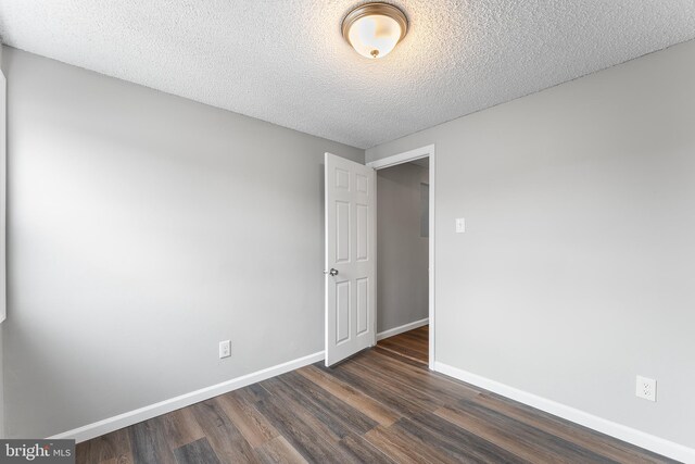 empty room with a textured ceiling and dark wood-type flooring