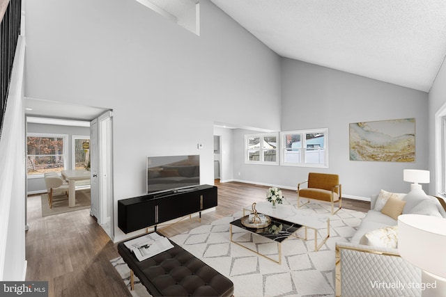 living room featuring wood-type flooring, a textured ceiling, and high vaulted ceiling