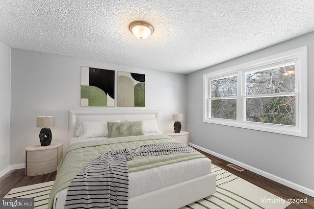 bedroom with dark hardwood / wood-style floors and a textured ceiling