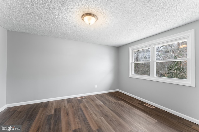 empty room with dark hardwood / wood-style floors and a textured ceiling