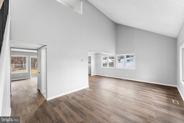 unfurnished living room featuring a textured ceiling, dark wood-type flooring, and high vaulted ceiling