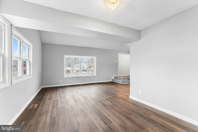 unfurnished living room with a textured ceiling and dark hardwood / wood-style flooring