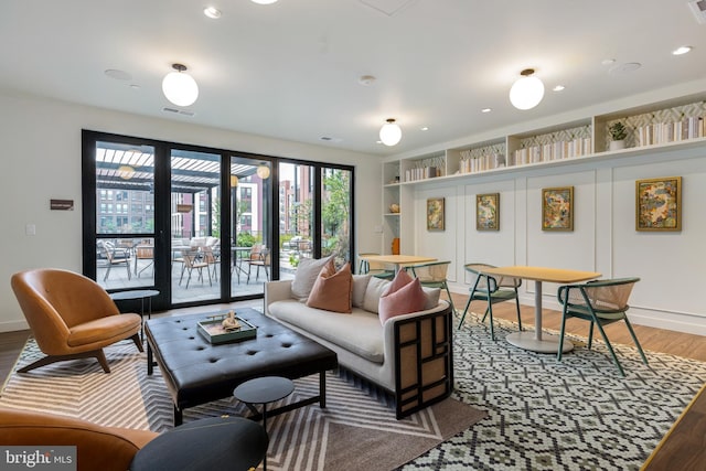 living room with built in features and wood-type flooring