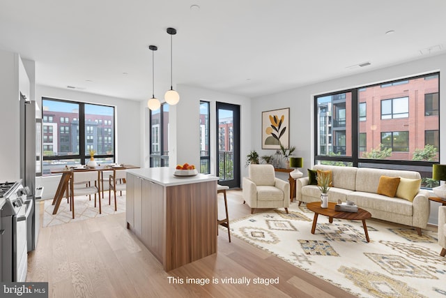 kitchen featuring gas stove, a kitchen island, light hardwood / wood-style floors, and decorative light fixtures