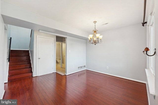 empty room featuring dark hardwood / wood-style flooring and an inviting chandelier