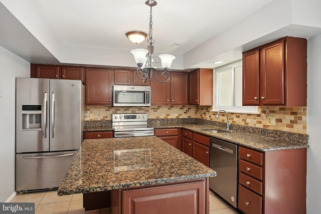 kitchen featuring stainless steel appliances, sink, pendant lighting, an inviting chandelier, and a center island