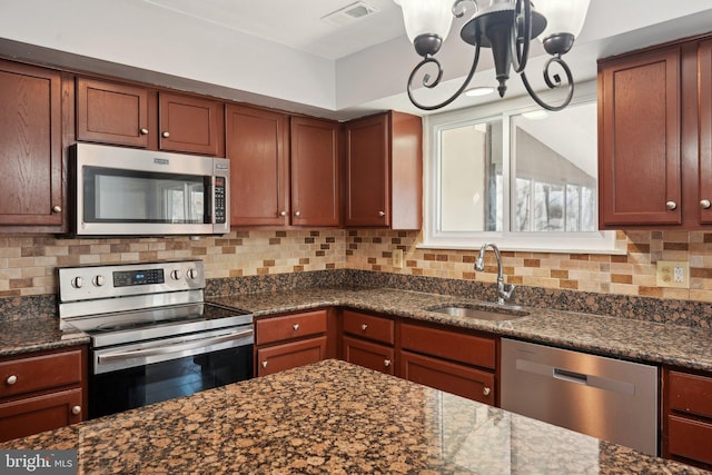 kitchen featuring decorative backsplash, sink, stainless steel appliances, and dark stone counters