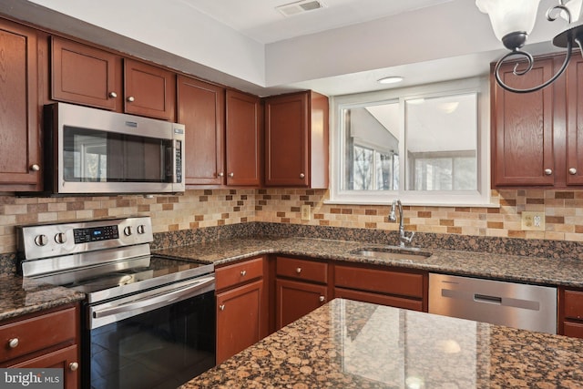 kitchen with dark stone countertops, sink, and appliances with stainless steel finishes