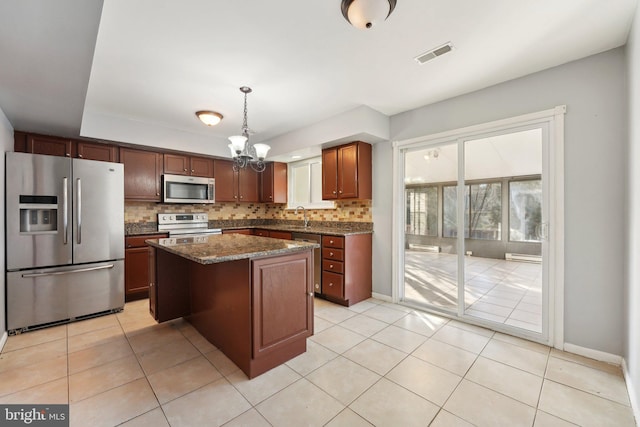 kitchen featuring pendant lighting, a center island, sink, light tile patterned floors, and stainless steel appliances