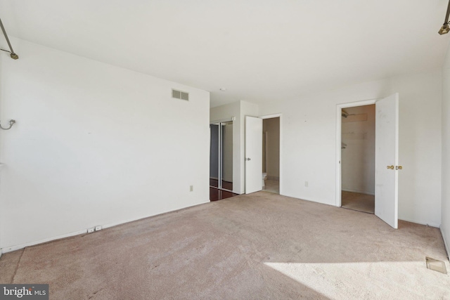 unfurnished bedroom with carpet flooring, a walk in closet, and a closet