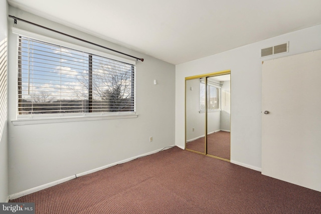 unfurnished bedroom with dark carpet and a closet