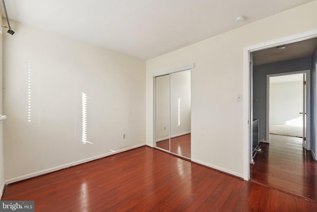 unfurnished bedroom with dark hardwood / wood-style floors and a closet