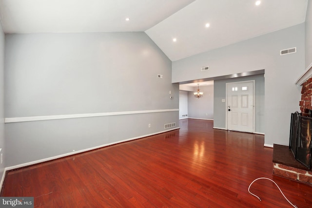 unfurnished living room with dark hardwood / wood-style flooring, high vaulted ceiling, and a chandelier