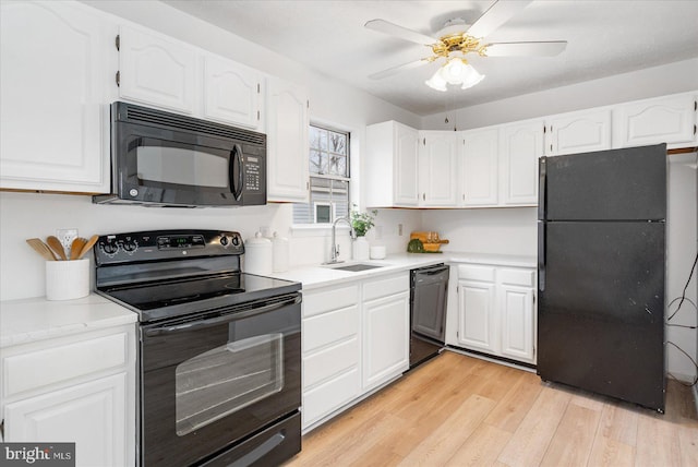 kitchen featuring sink, white cabinets, black appliances, and light hardwood / wood-style flooring