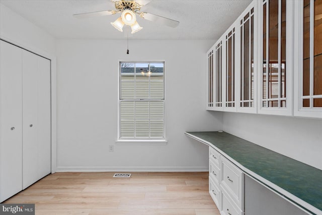 interior space with ceiling fan, light hardwood / wood-style floors, and a textured ceiling