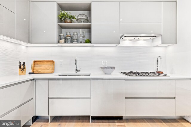 kitchen with stainless steel gas cooktop, white cabinetry, sink, and extractor fan