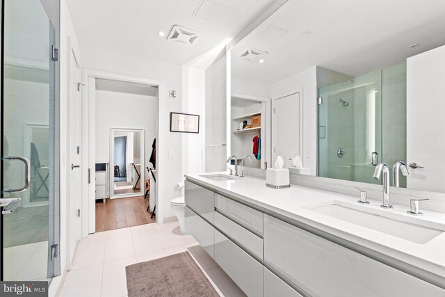 bathroom with tile patterned flooring, vanity, a shower with shower door, and toilet