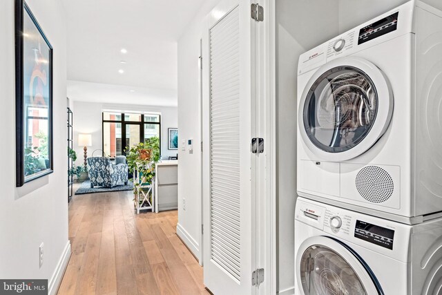 laundry room with light hardwood / wood-style floors and stacked washer and clothes dryer