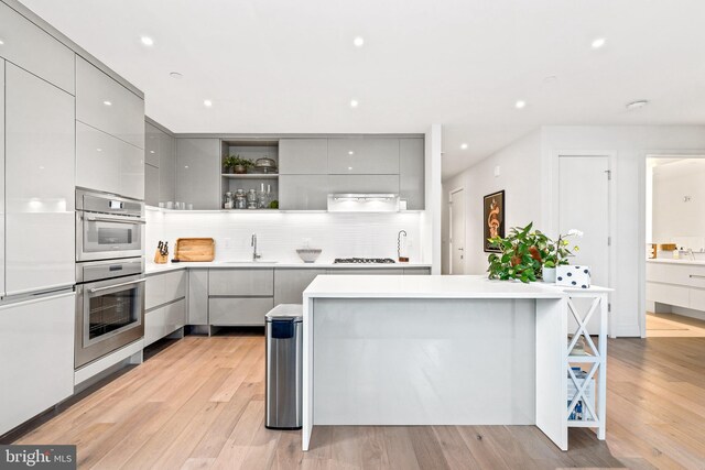 kitchen featuring gray cabinets, gas stovetop, light wood-type flooring, and sink