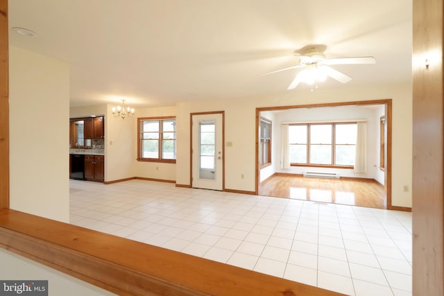 empty room featuring a baseboard heating unit, light tile patterned floors, ceiling fan with notable chandelier, and baseboards