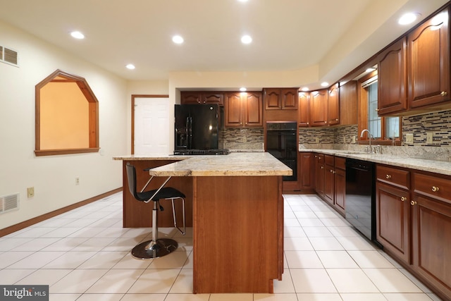 kitchen with a breakfast bar area, light tile patterned floors, a kitchen island, decorative backsplash, and black appliances