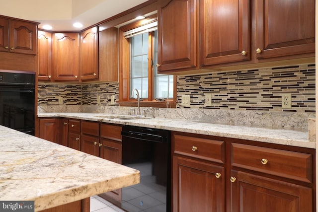 kitchen with black appliances, light stone counters, tasteful backsplash, and a sink