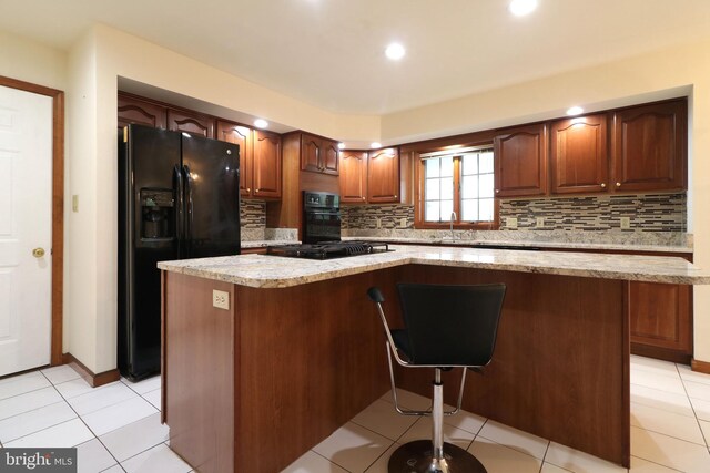 kitchen with a center island, decorative backsplash, black appliances, and light tile patterned floors