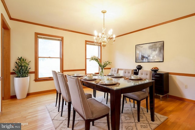 dining space featuring baseboards, light wood-style floors, a chandelier, and ornamental molding