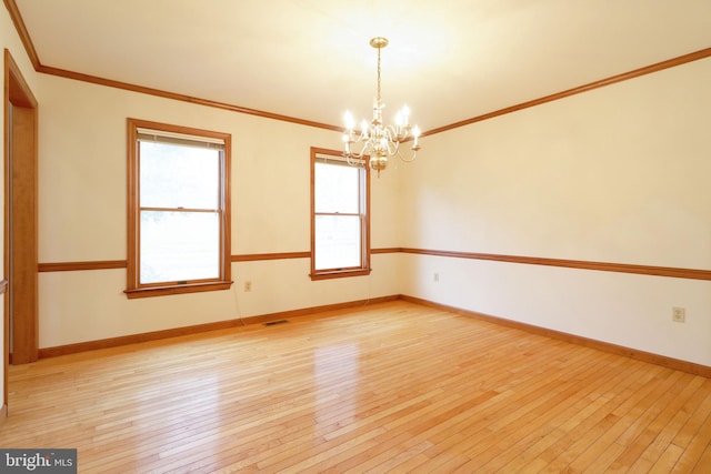empty room featuring light wood finished floors, visible vents, crown molding, baseboards, and a chandelier
