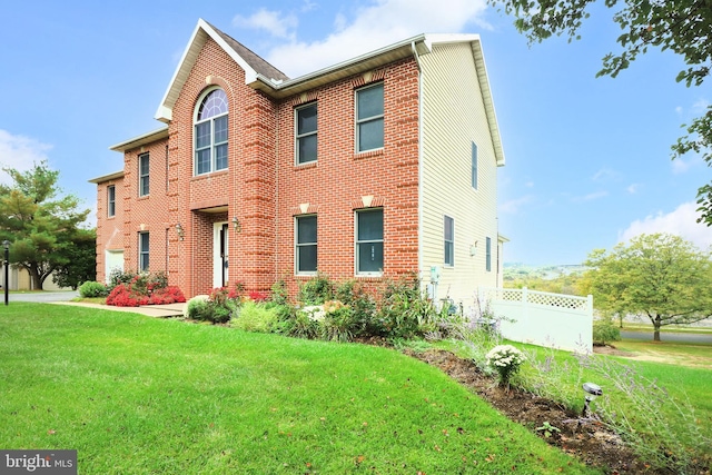view of front of home featuring brick siding, a front yard, and fence