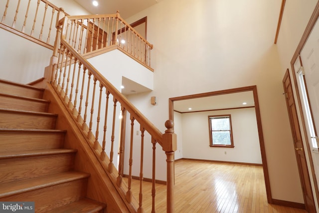 stairway with hardwood / wood-style flooring, baseboards, and a towering ceiling
