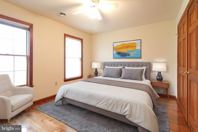 bedroom featuring light wood-style flooring, a ceiling fan, baseboards, and a closet