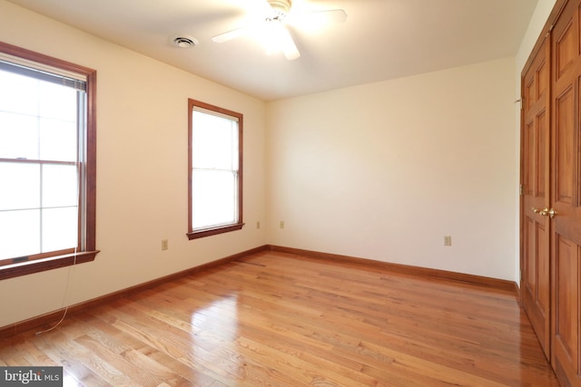 empty room featuring visible vents, baseboards, a ceiling fan, and light wood finished floors