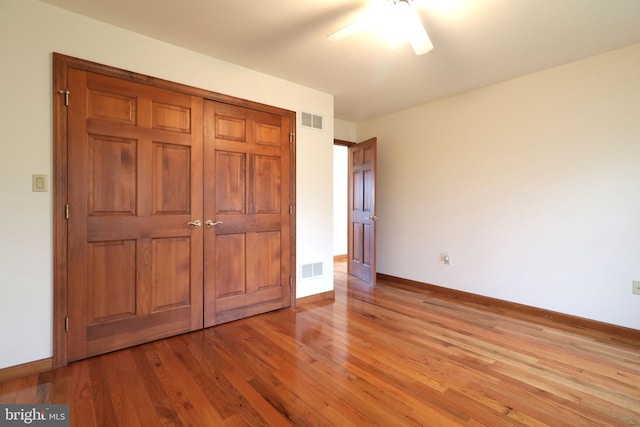 unfurnished bedroom with visible vents, baseboards, wood finished floors, and a ceiling fan