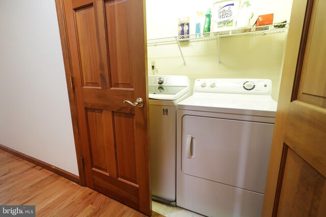 laundry area featuring washer and dryer, baseboards, light wood-style floors, and laundry area
