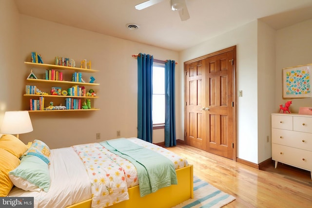 bedroom featuring light wood finished floors, visible vents, ceiling fan, baseboards, and a closet