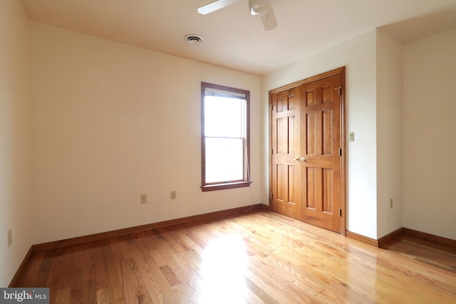 unfurnished bedroom featuring light wood-type flooring, visible vents, a ceiling fan, a closet, and baseboards