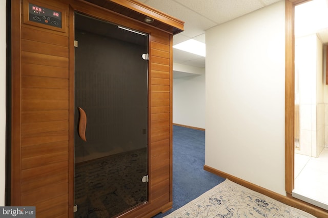interior space featuring carpet flooring, a paneled ceiling, baseboards, and a sauna