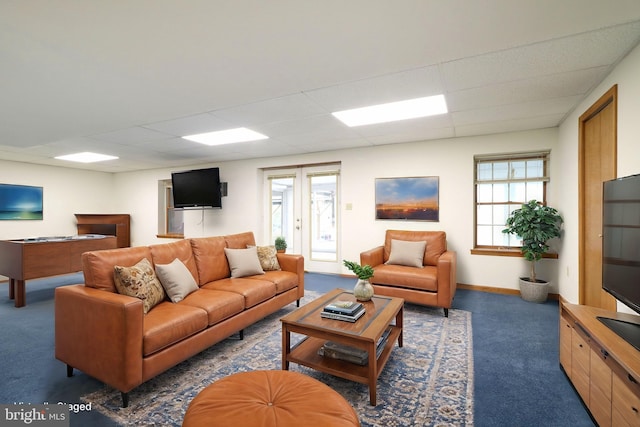living room featuring baseboards, a paneled ceiling, and carpet