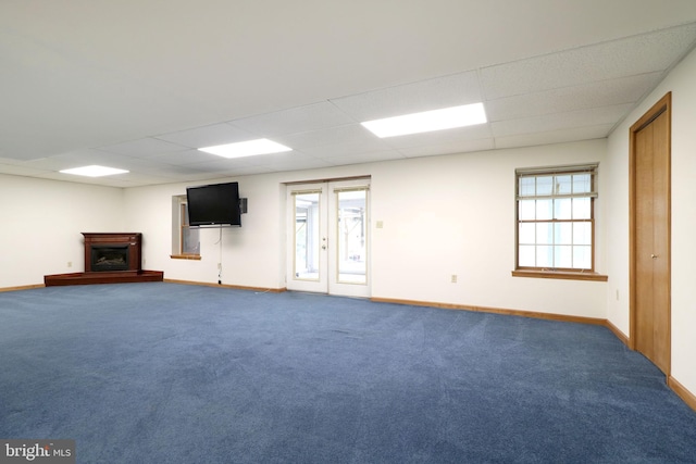 interior space with baseboards, a paneled ceiling, carpet floors, and a fireplace with raised hearth