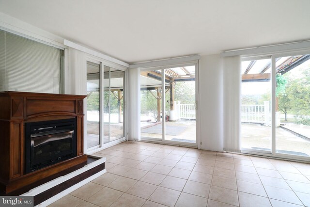 unfurnished living room with light tile patterned floors, a sunroom, and expansive windows