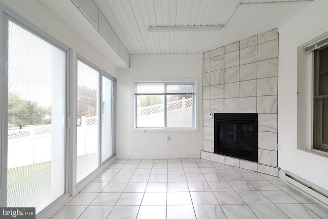 unfurnished sunroom with a tiled fireplace and a baseboard heating unit