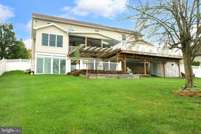 back of property with a deck, a yard, and fence
